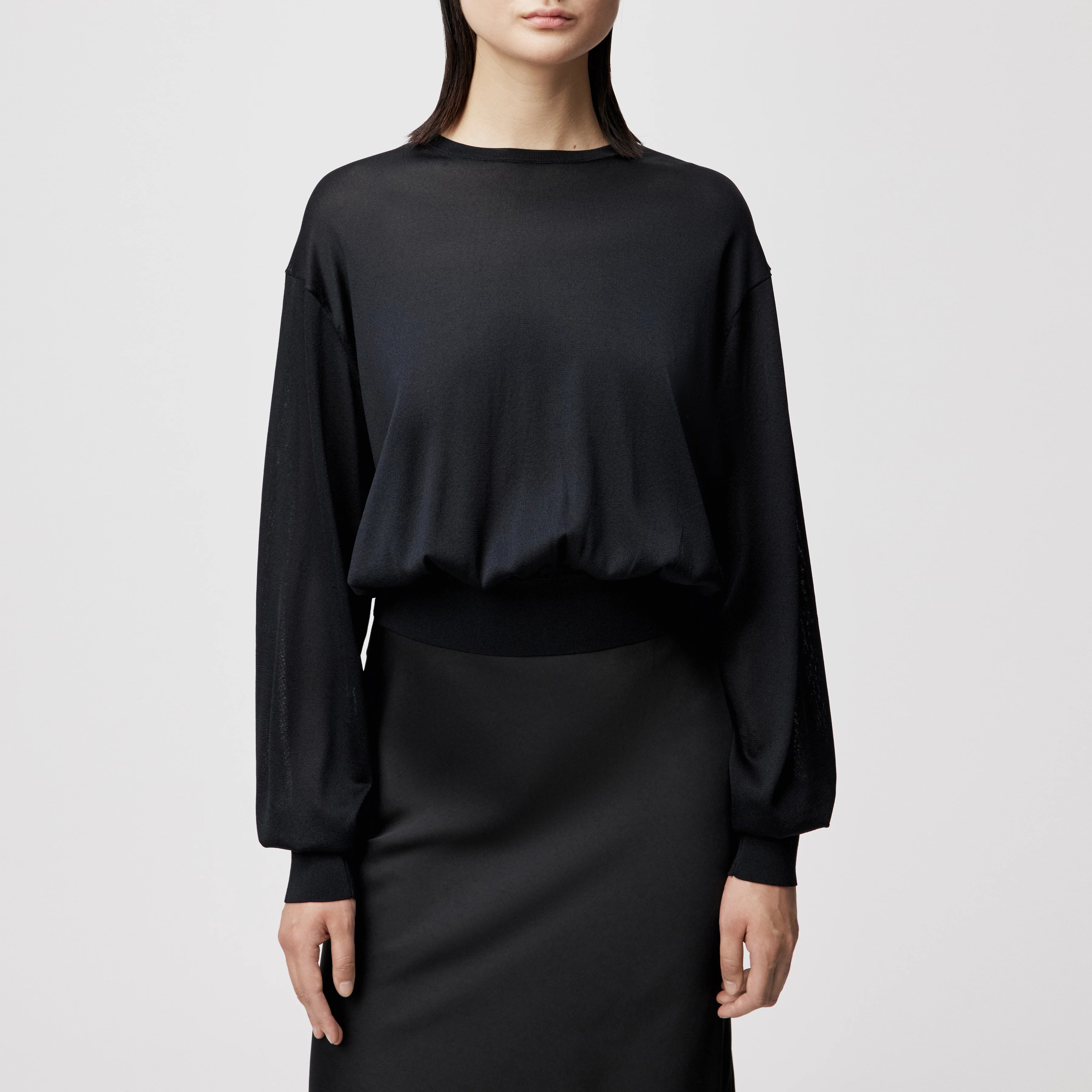 Model trägt den oversized DRYKORN Strickpullover TALOMINA mit Ballonärmeln und Rundhalsausschnitt aus feinem Acetat in lässiger Passform.