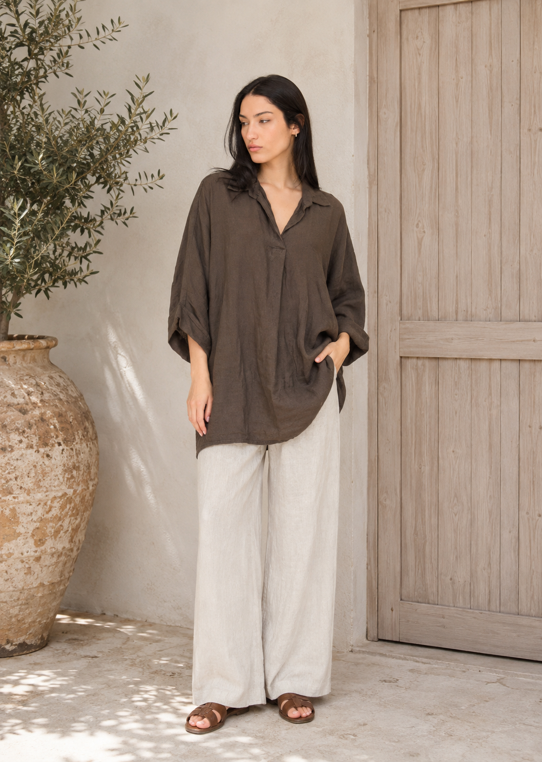Oversize Leinenbluse aus 100 % Leinen in Coffee kombiniert mit einer hellen Leinenhose in mediterranem Ambiente.