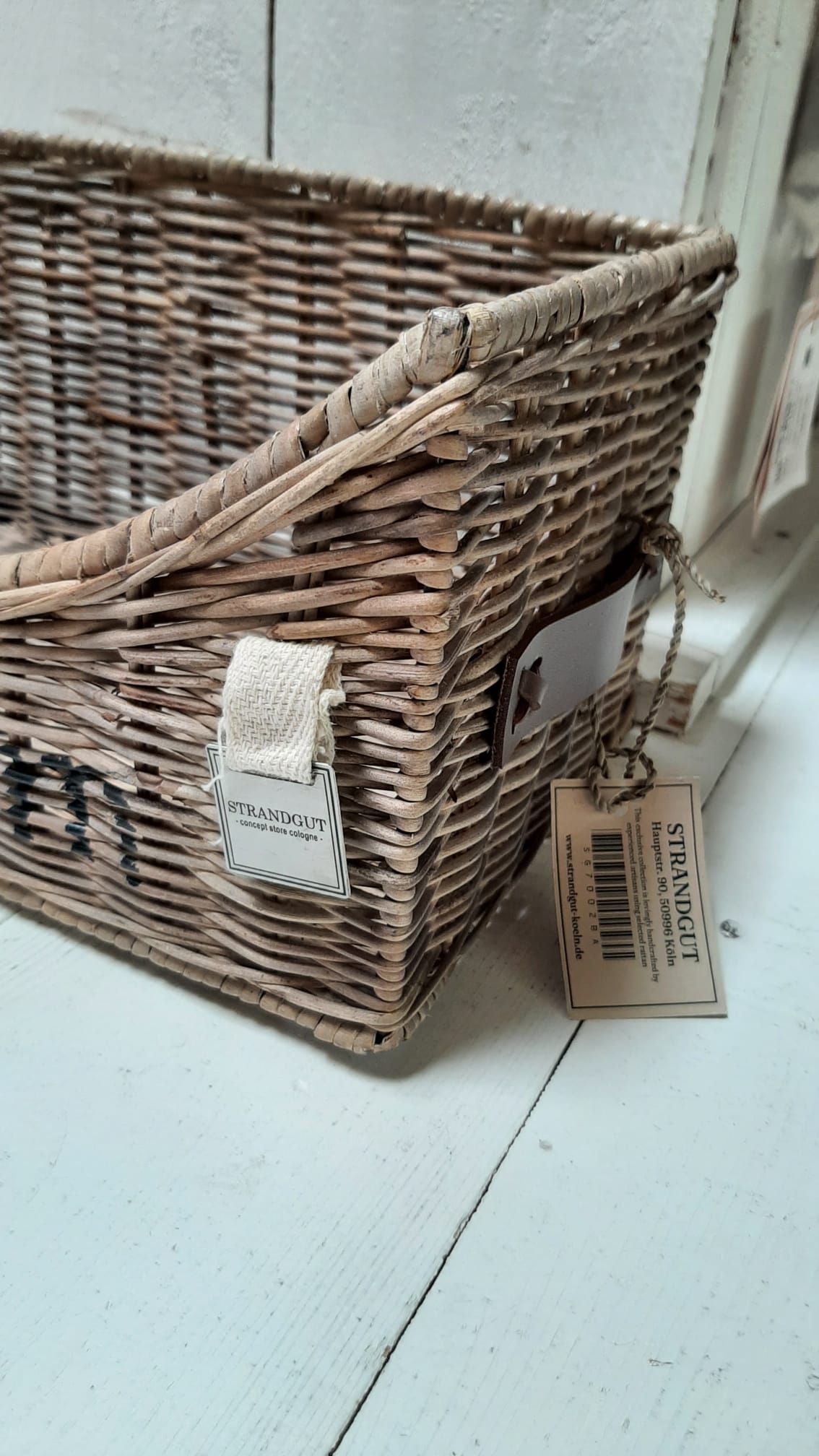 Rattan-Aufbewahrungskorb „Bathroom“ mit eingerollten Handtüchern und Badebürsten als stilvolle Badezimmerorganisation im natürlichen Landhaus- und Beachhouse-Stil.Seitenansicht