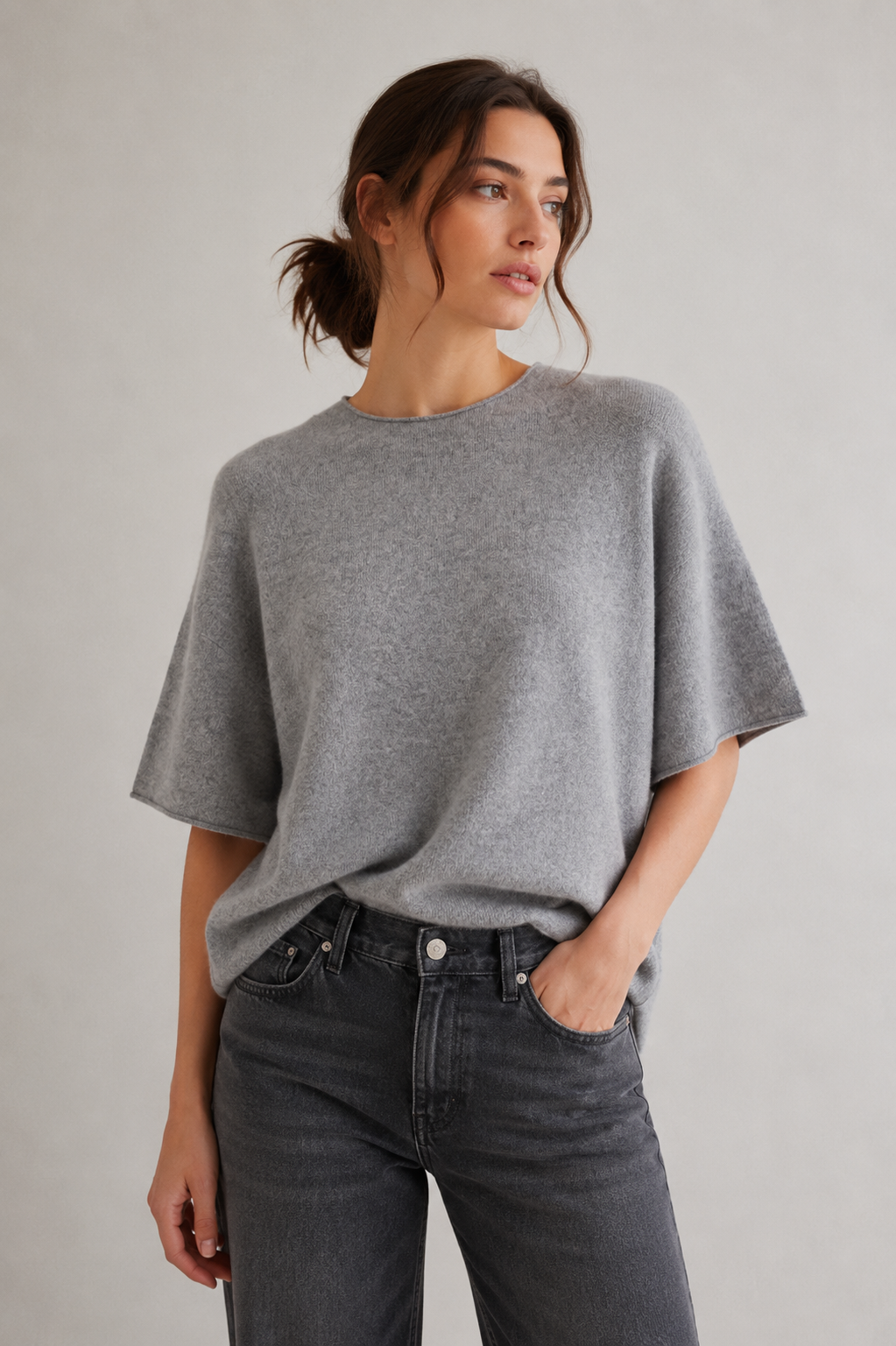 Model trägt den hellgrau melierten DRYKORN MOENY Strickpullover aus Baumwoll-Kaschmir-Mischung mit lockerem Boxy Fit und weiten Ärmeln.