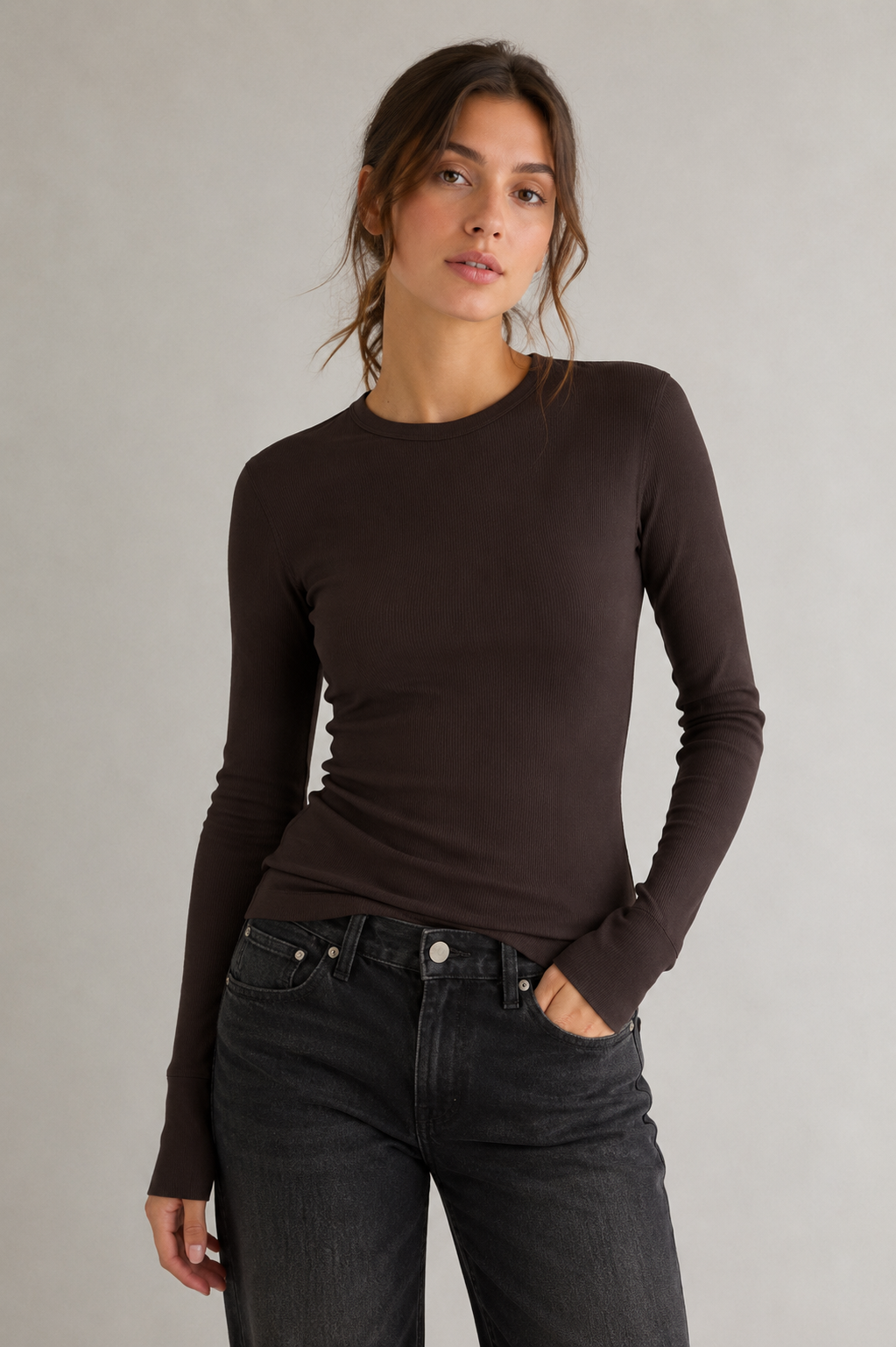 Model trägt das dunkelbraune DRYKORN NURIT_2 Longsleeve aus feiner Baumwoll-Rippqualität mit schmaler Passform und Rundhalsausschnitt.