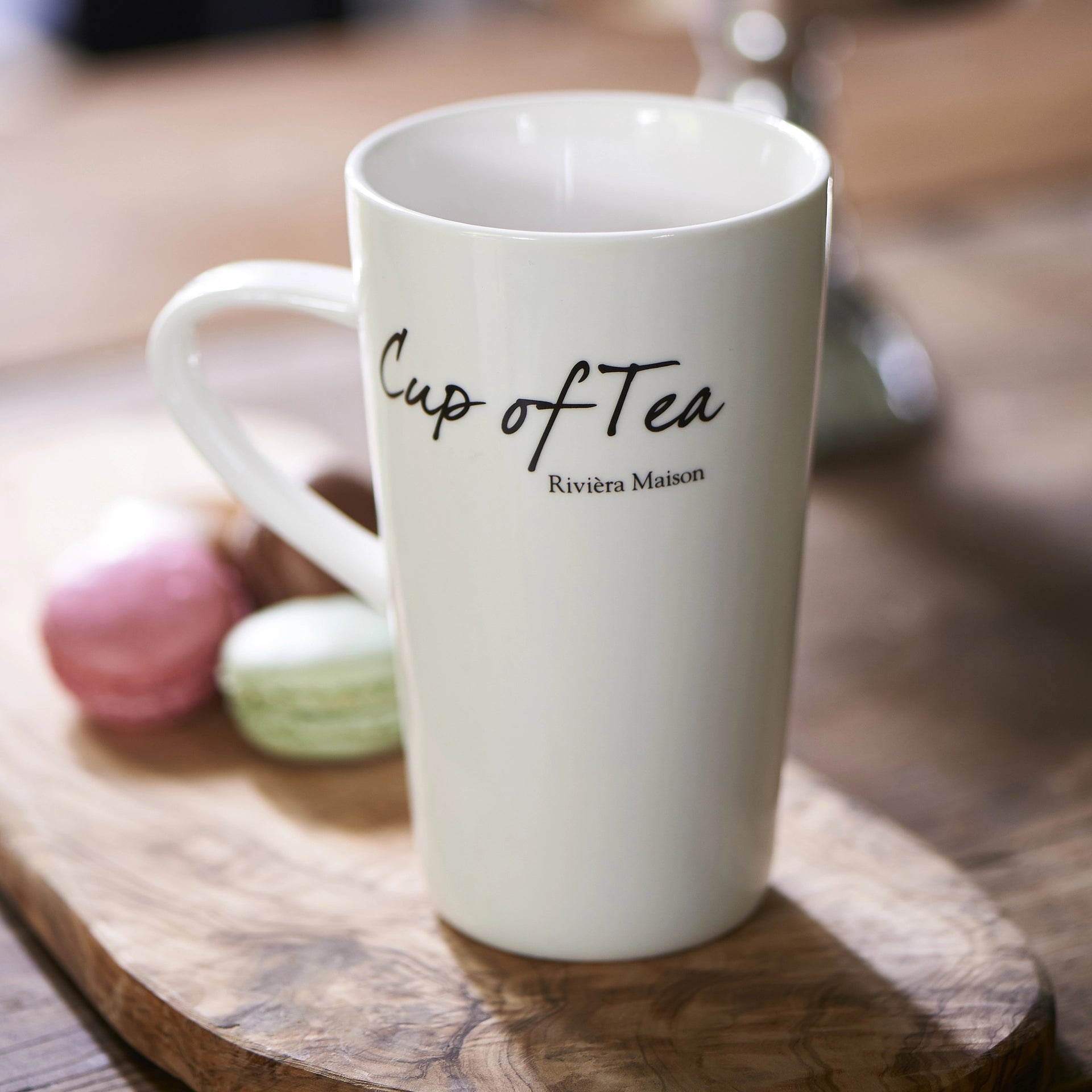 Weiße Teetasse aus Porzellan von Riviera Maison mit schwarzer „Cup of Tea“-Aufschrift.