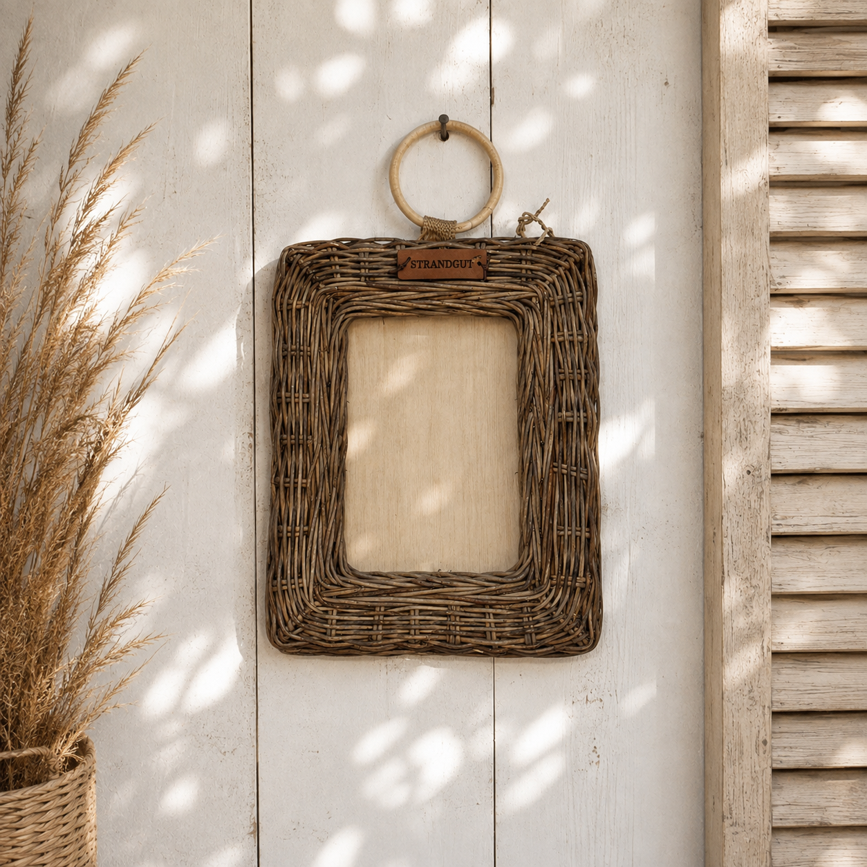 STRANDGUT Rattan Bilderrahmen im Hochformat an heller Holzwand im natürlichen Strandhausstil