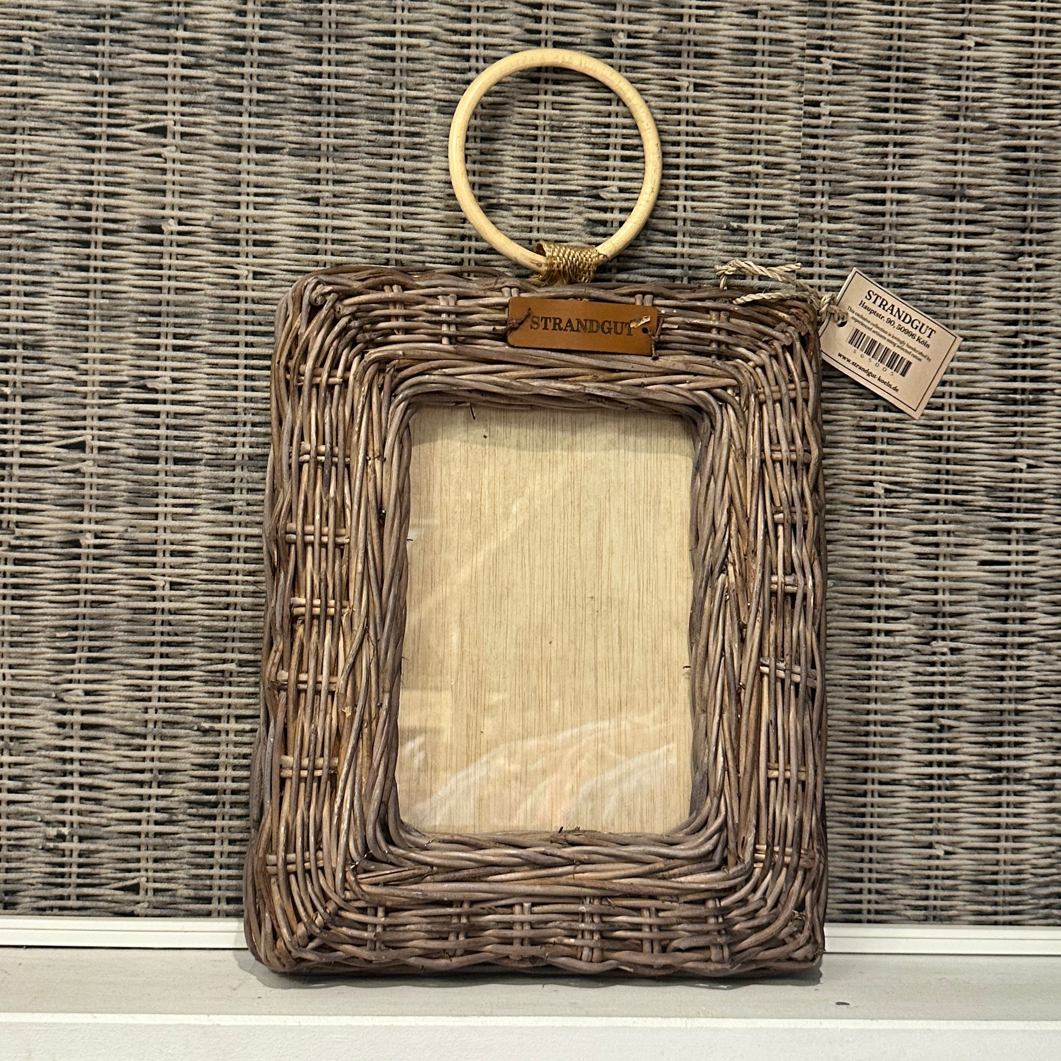 STRANDGUT Rattan Bilderrahmen im Hochformat an heller Holzwand im natürlichen Strandhausstil