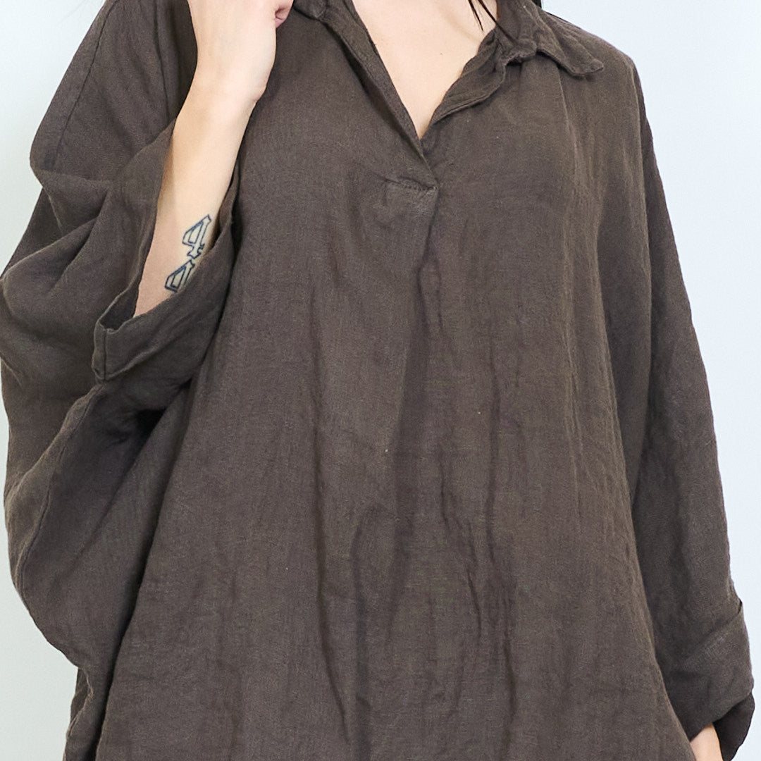 Oversize Leinenbluse aus 100 % Leinen in Coffee kombiniert mit einer hellen Leinenhose in mediterranem Ambiente.