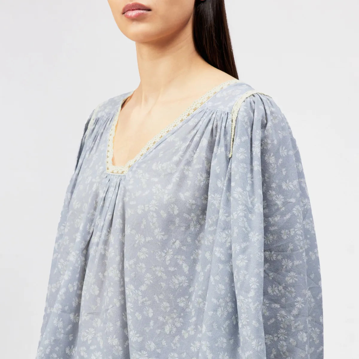 DRYKORN ISMARA Babydoll Tunika-Bluse mit hellblauem Blumenprint, Spitzenborte am Ausschnitt, langen Ärmeln und lockerer A-Linien-Passform.