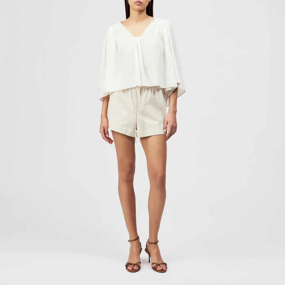 Drykorn Tunika-Bluse ISMARA in Cremeweiß mit weitem Ärmel, Spitzenborte am Ausschnitt und fließender A-Linien-Silhouette. Feminine Sommerbluse aus Baumwoll-Viskose-Mix mit leichter Crêpe-Struktur.
