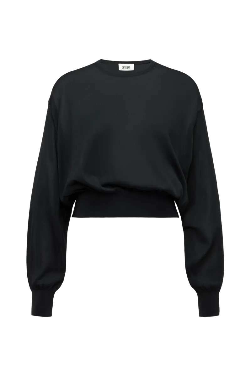 Model trägt den oversized DRYKORN Strickpullover TALOMINA mit Ballonärmeln und Rundhalsausschnitt aus feinem Acetat in lässiger Passform.