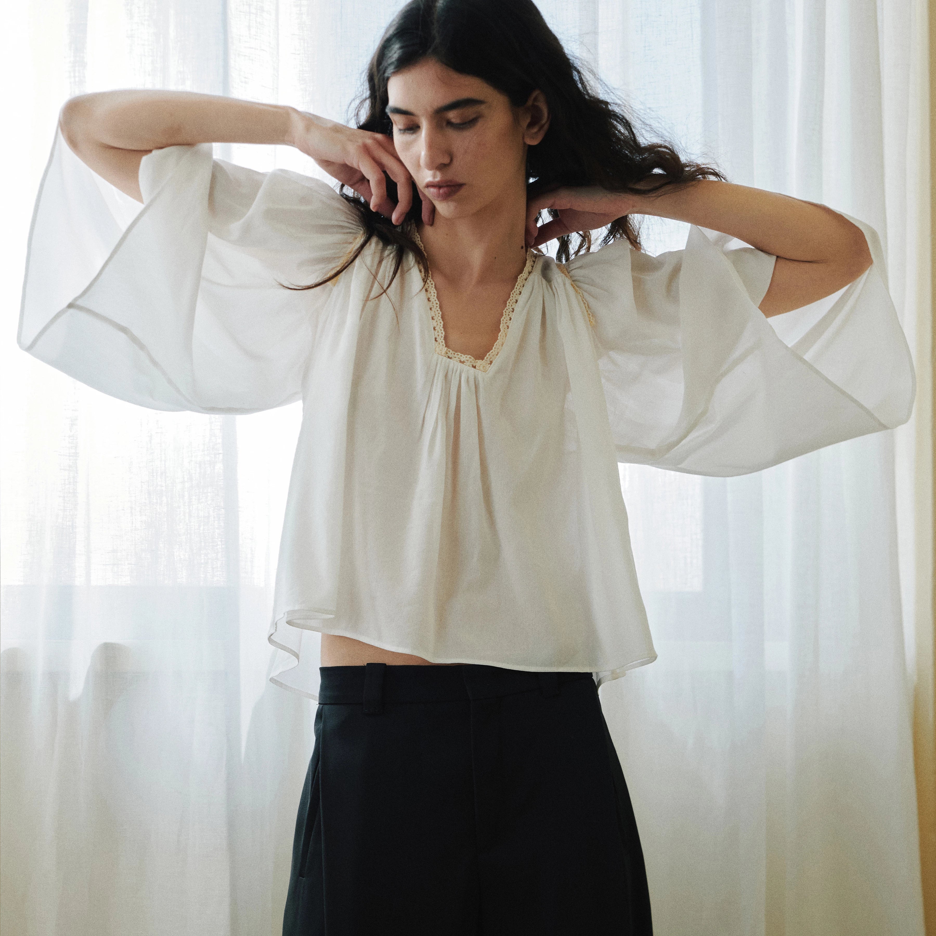 Drykorn Tunika-Bluse ISMARA in Cremeweiß mit weitem Ärmel, Spitzenborte am Ausschnitt und fließender A-Linien-Silhouette. Feminine Sommerbluse aus Baumwoll-Viskose-Mix mit leichter Crêpe-Struktur.