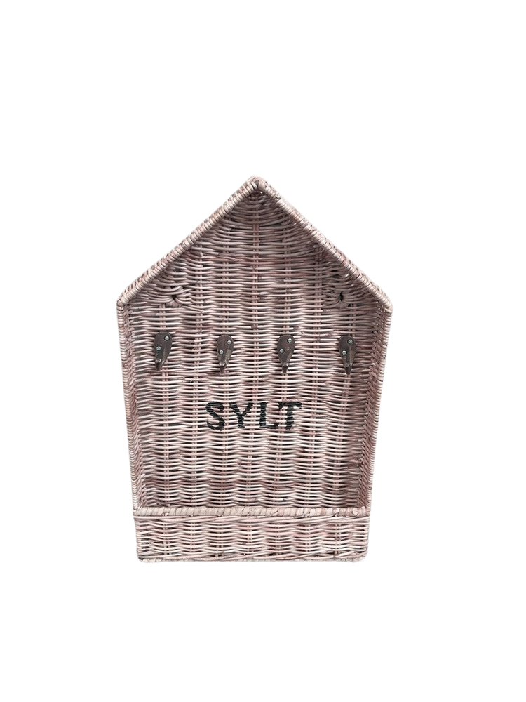 Handgefertigter Rattan Schlüsselkasten mit SYLT-Aufschrift und Schlüssel an Metallhaken im hellen Strandhaus im Coastal-Style.